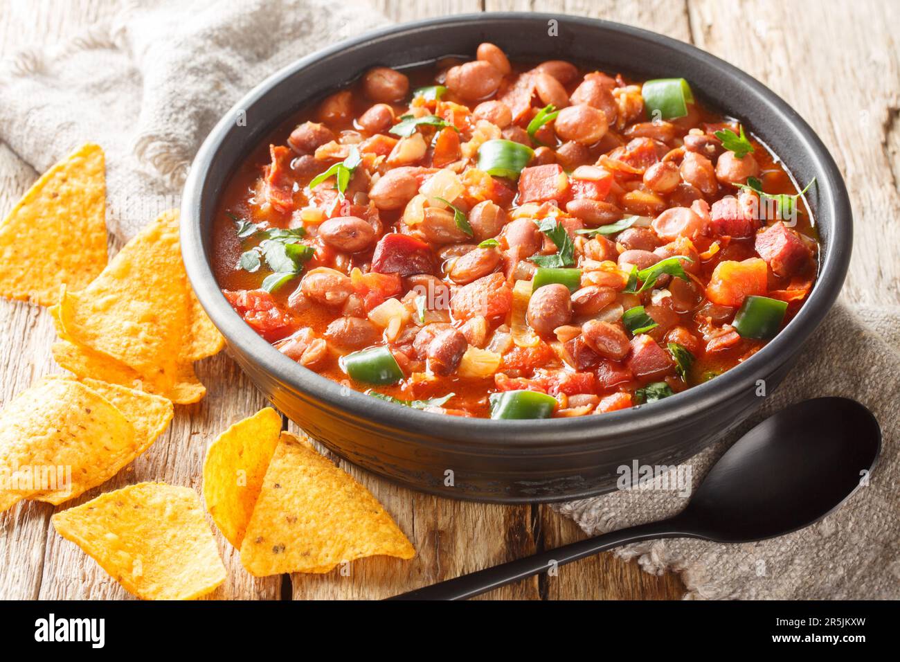 Haricots bruns mexicains à base de haricots pinto, bacon, jambon, chorizo, piments, tomates et épices sur le bol de la table. Horizontale Banque D'Images