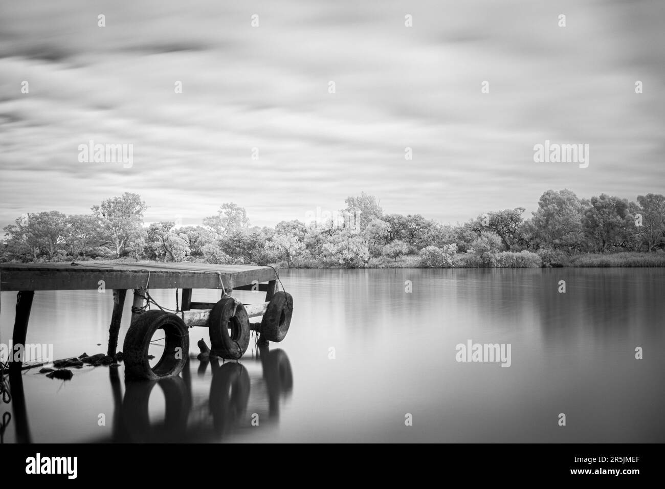 quai en bois noir et blanc longue exposition avec protections de pneus sur la rivière murray Banque D'Images