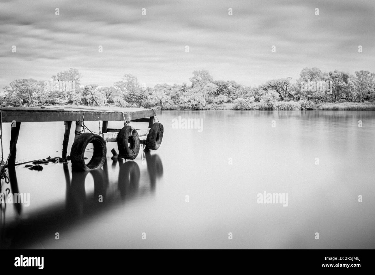 quai en bois noir et blanc longue exposition avec protections de pneus sur la rivière murray Banque D'Images