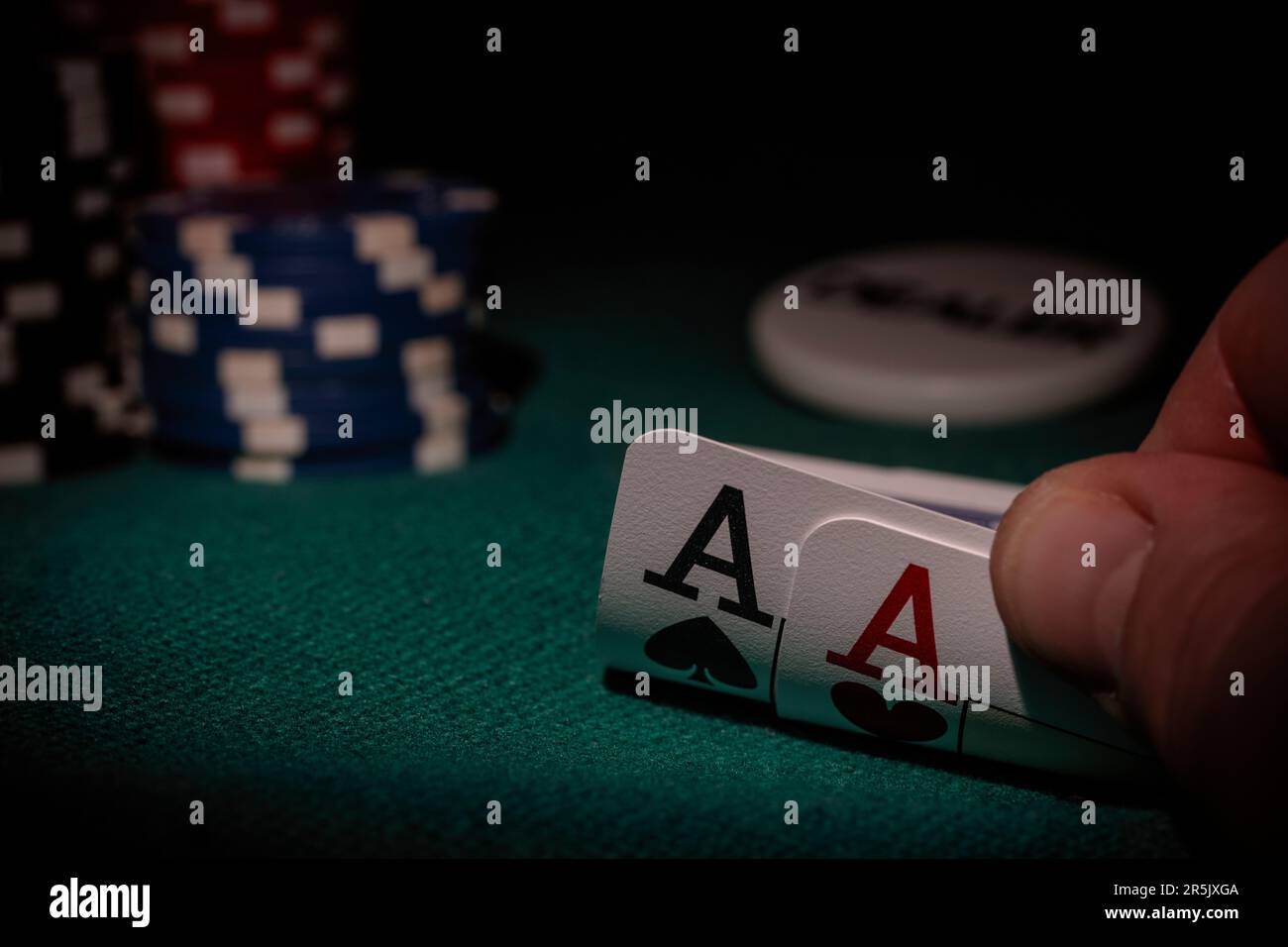 Une table de poker avec des jetons, un bouton revendeur et deux as dans la main du joueur Banque D'Images