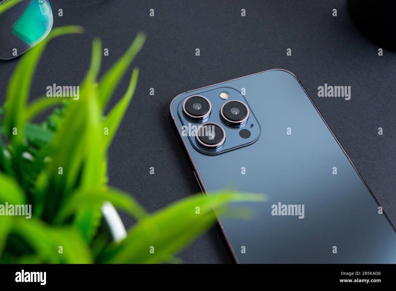 Arrière du téléphone avec caméras et capteurs. Téléphone posé sur la table noire et accusé de feuilles vertes Banque D'Images