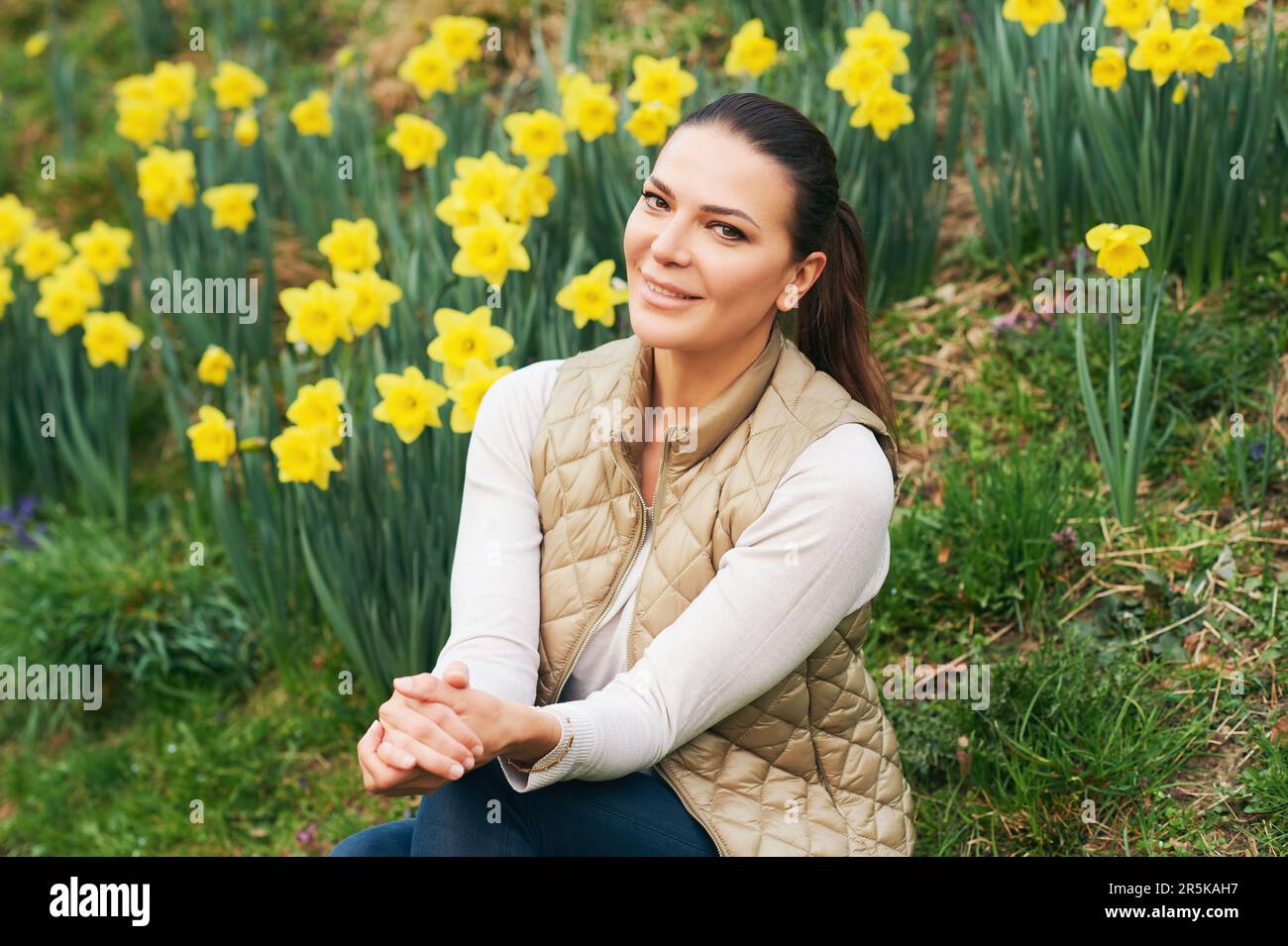 Portrait de printemps de la jeune belle femme assise dans un champ de jonquilles en fleurs Banque D'Images