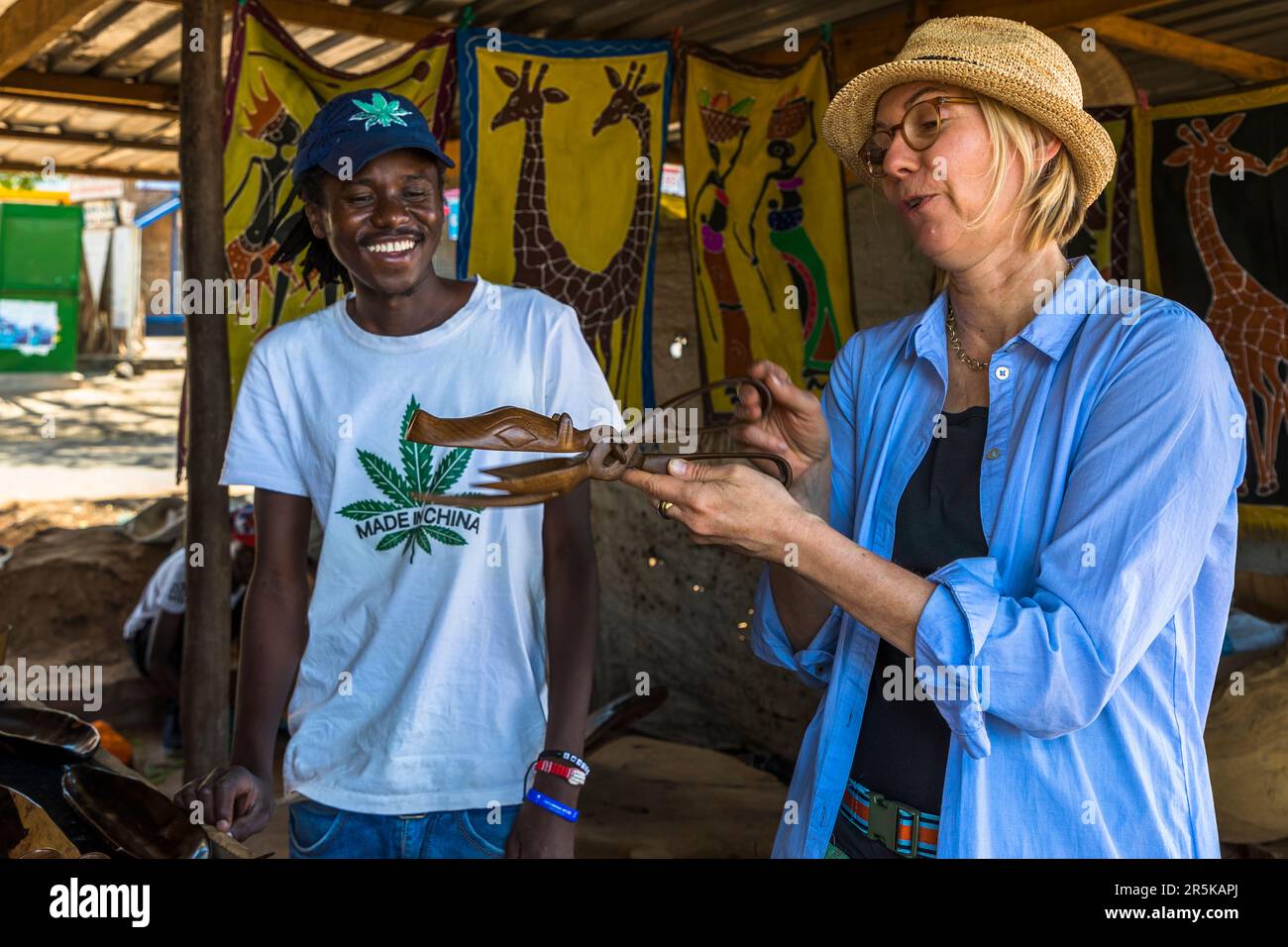 Marché de souvenirs à Lilongwe. Sculptures en bois, ici serveurs de salade en forme d'hippopotame. Le vendeur porte un T-shirt avec l'empreinte faite en Chine et vend également des serveurs de salade sculptés à la main en forme de pinces crocodile. Marché Curio à Lilongwe, Malawi Banque D'Images