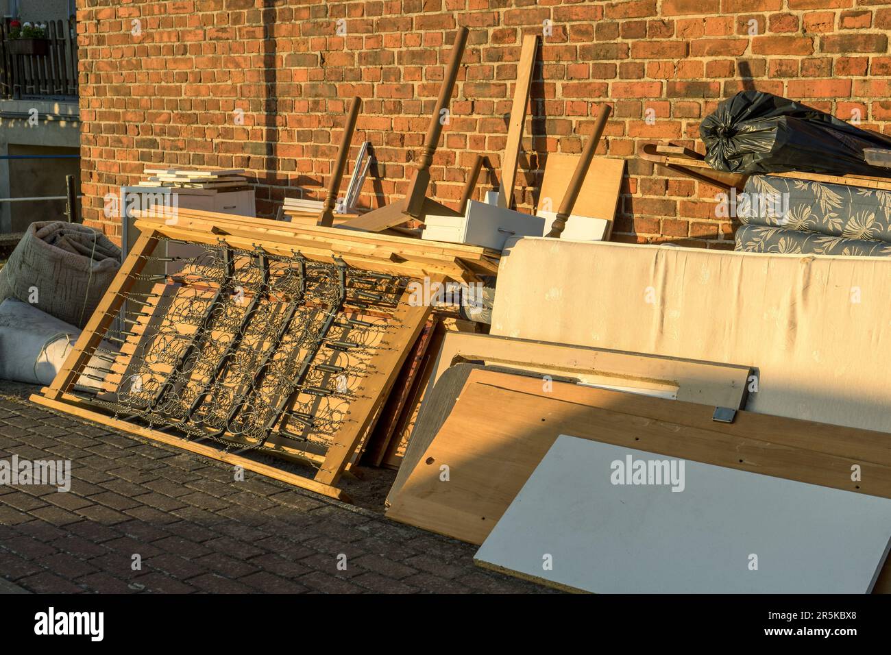 Tas de déchets volumineux avec matelas, cadre de lit, table et placards au bord de la route Banque D'Images