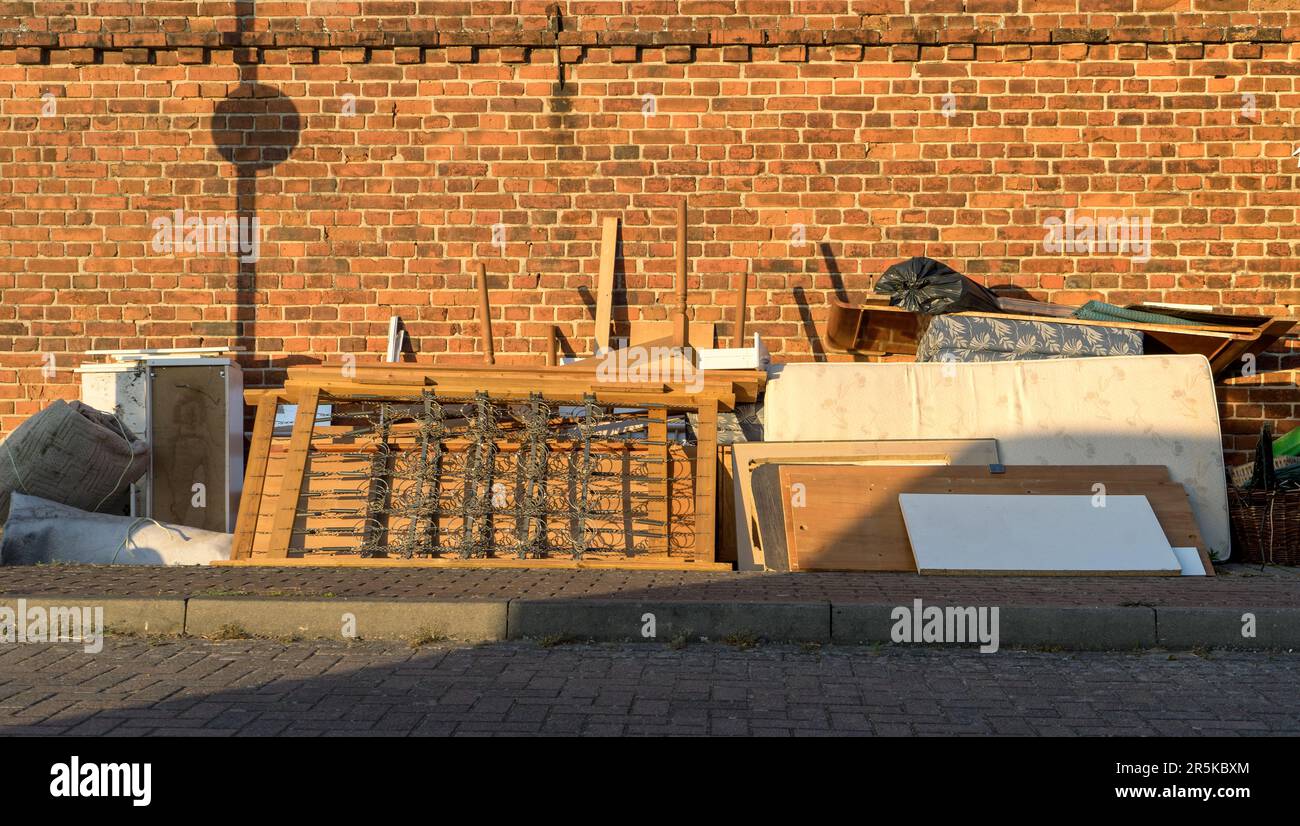 Tas de déchets volumineux avec matelas, cadre de lit, table et placards au bord de la route Banque D'Images