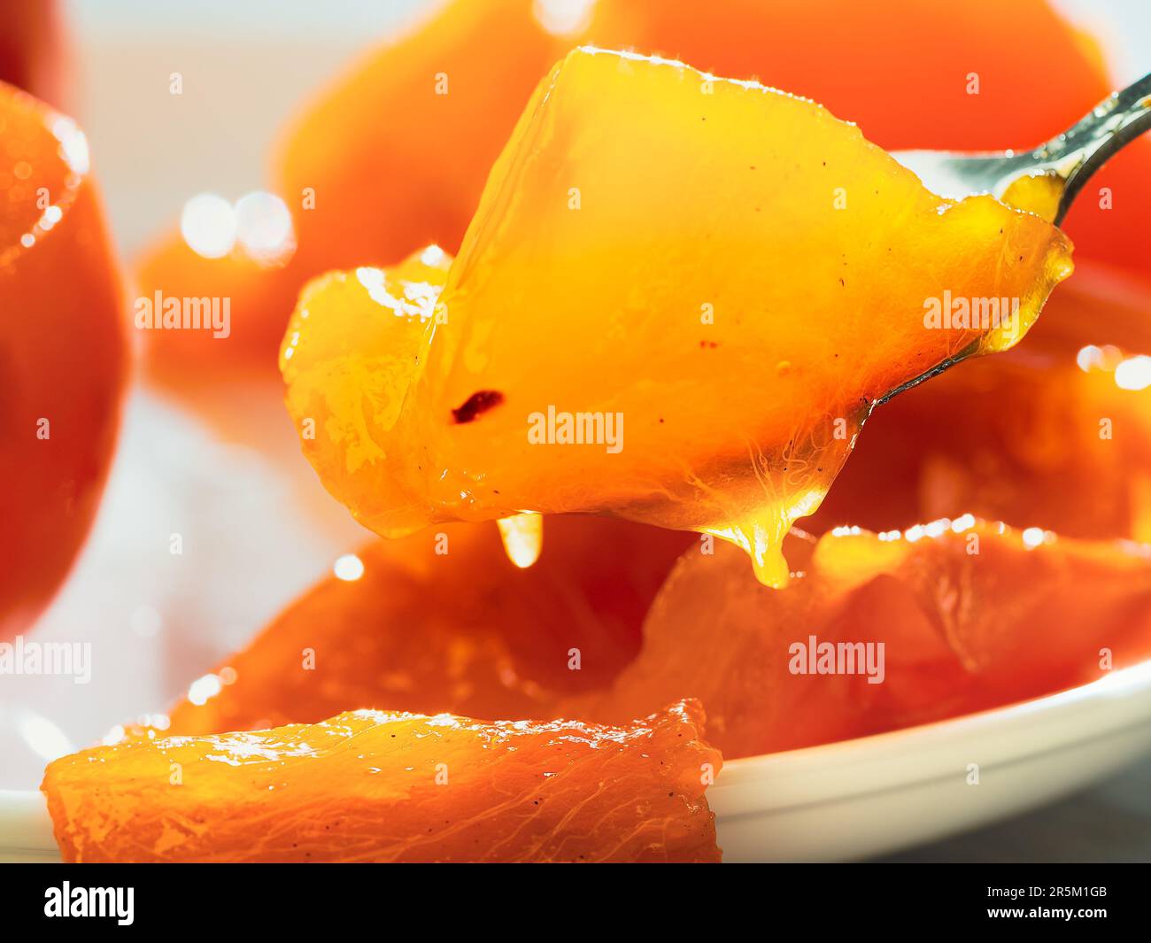 Un pésimmon doux mûr à l'orange se trouve sur une assiette blanche, prête à manger. Banque D'Images