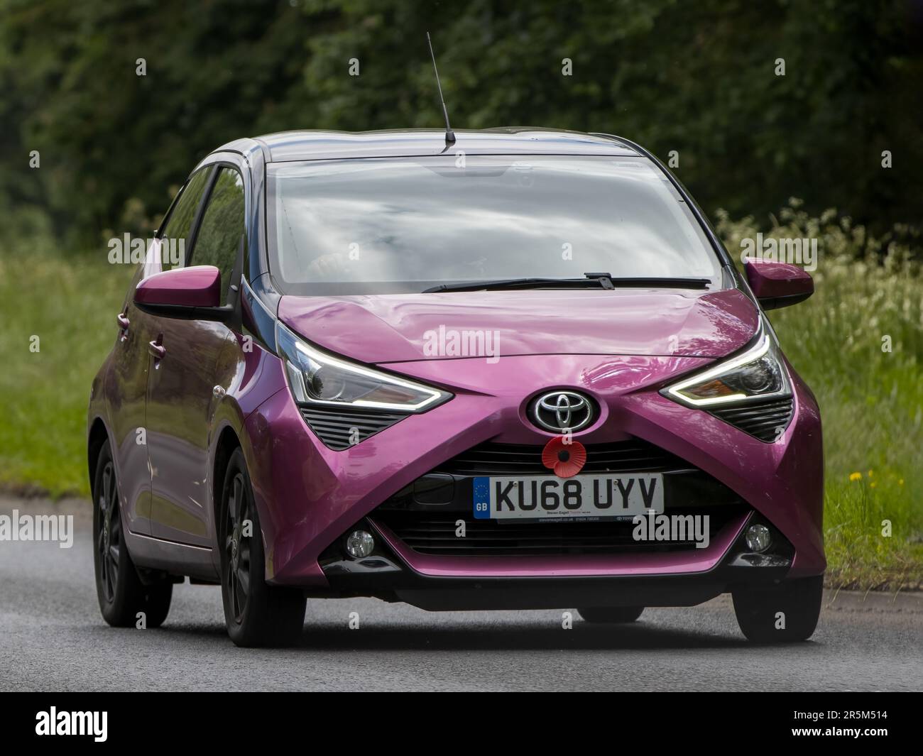 Stony Stratford, Royaume-Uni - 2 juin 2023 : 2018 Toyota AYGO violet avec un souvenir coquelicot voyageant sur une route de campagne anglaise Banque D'Images