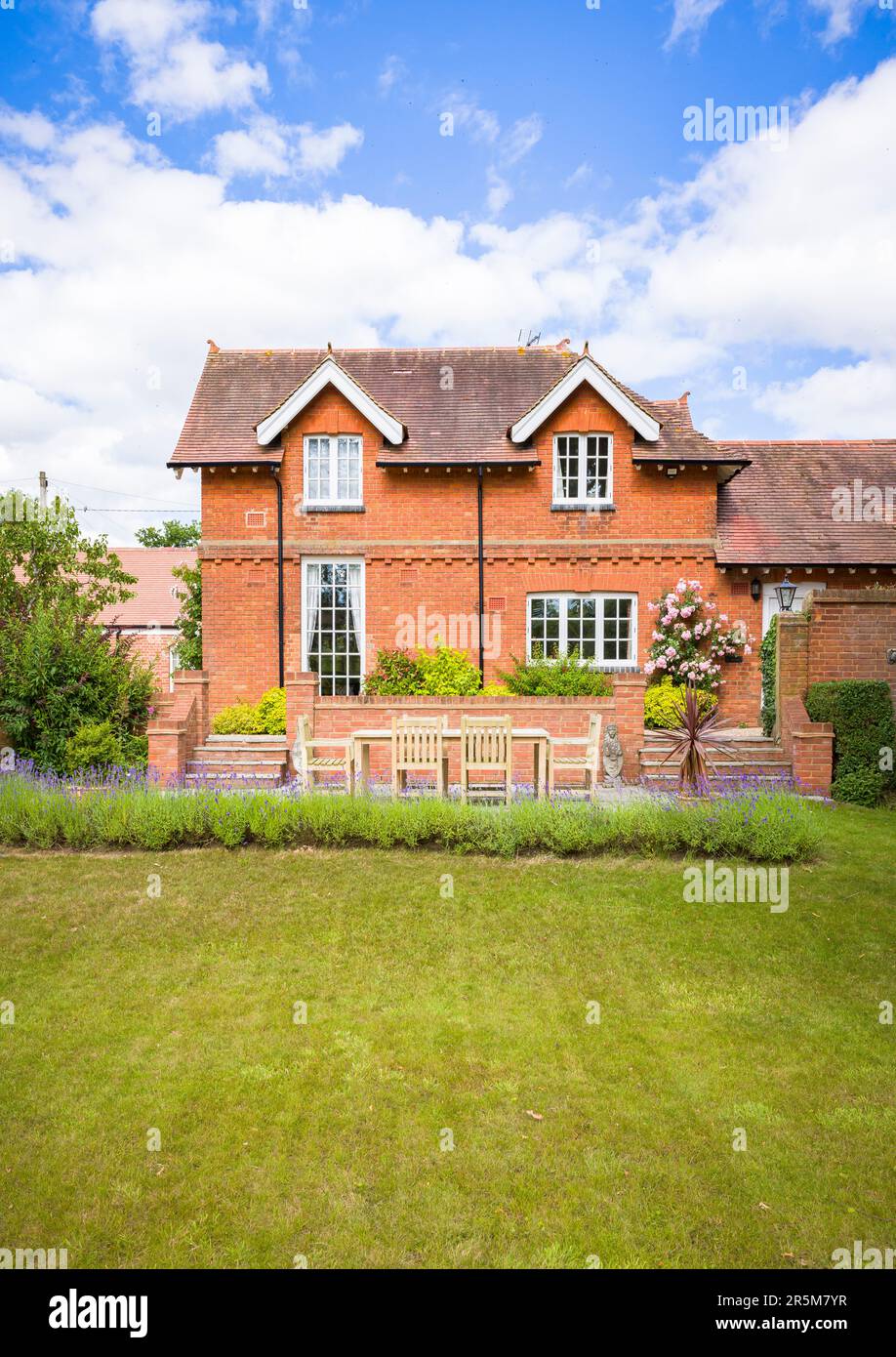 Grande maison de campagne britannique et jardin en été avec pelouse et terrasse avec meubles de jardin en teck Banque D'Images