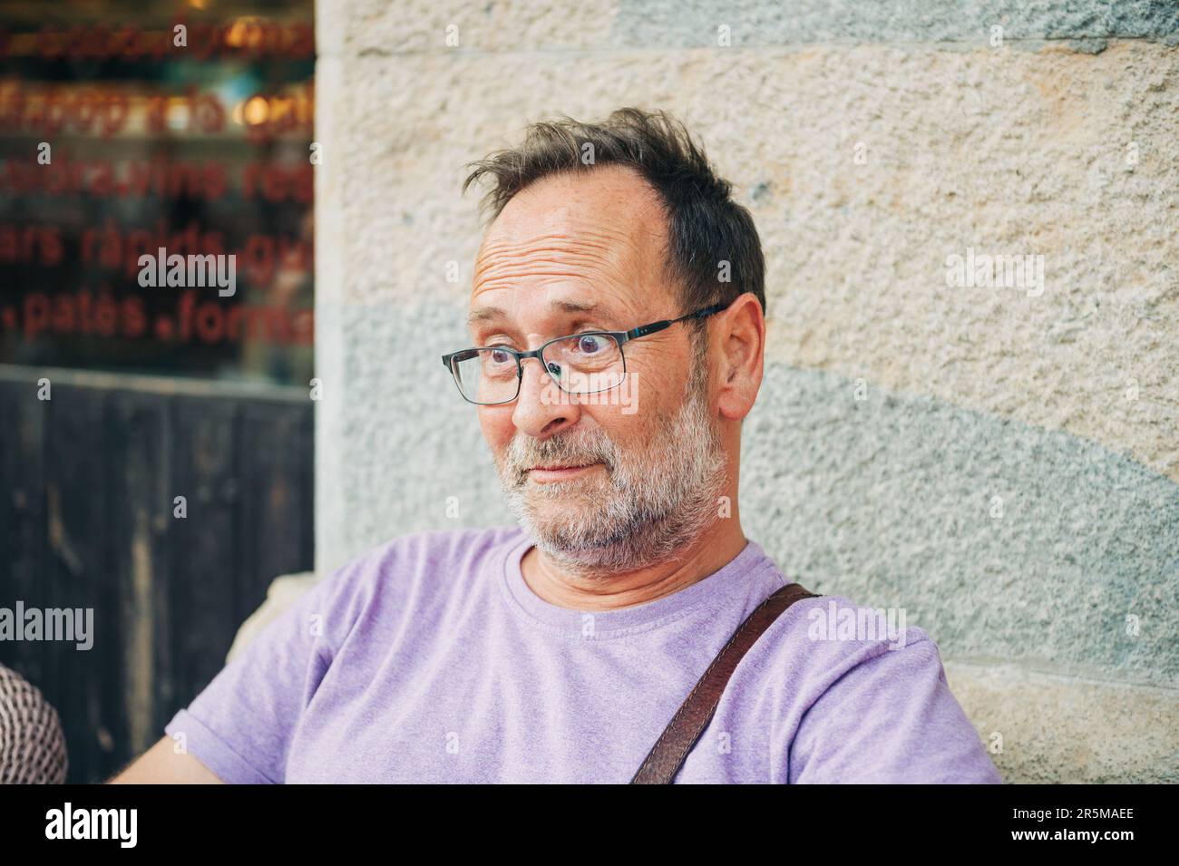 Portrait amusant de l'homme d'âge moyen surpris, se reposant à l'extérieur, portant un t-shirt violet et des lunettes Banque D'Images