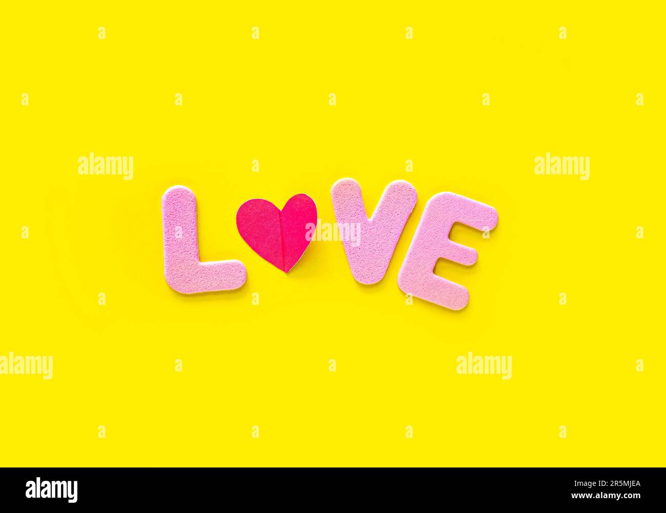 Texte d'amour rose isolé sur fond jaune avec espace de copie. Modèle de carte de voeux pour la Saint-Valentin. Concept de minimalisme. Banque D'Images