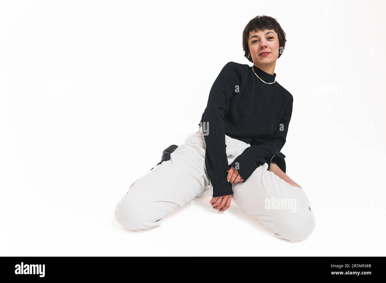 Arrière-plan blanc. Jeune femme posant sur ses genoux et laisse légèrement en arrière. Concept de modèle féminin. Photo de haute qualité Banque D'Images