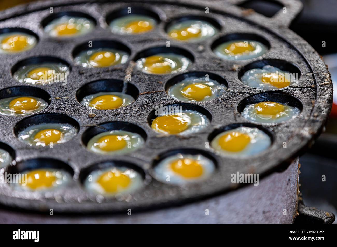 Œufs de caille frits dans un four thaïlandais, le résultat se présente comme un petit œuf frit. Saupoudrer de sauce soja et de poivre moulu. C'est un très grand pape Banque D'Images