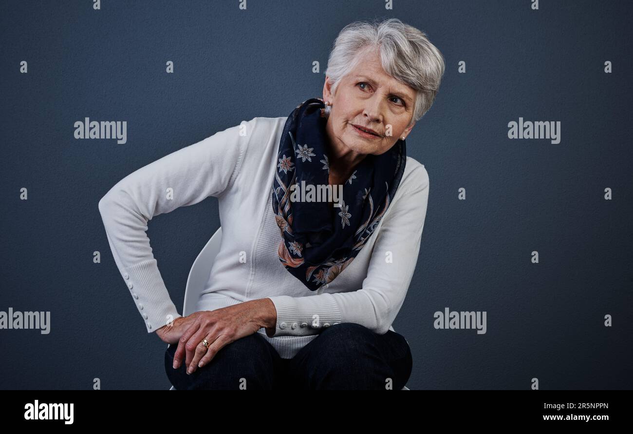 L'âge peut changer mais la classe reste la même. Photo studio d'une femme âgée assise avec une main sur la hanche tout en regardant au loin. Banque D'Images