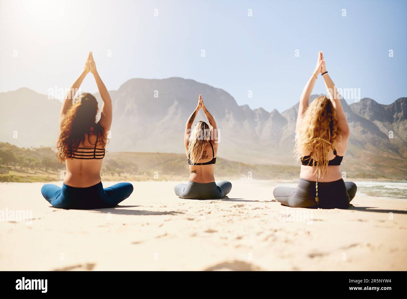 Étaient sur le chemin d'une vie plus paisible. Vue arrière de trois jeunes femmes pratiquant le yoga sur la plage. Banque D'Images