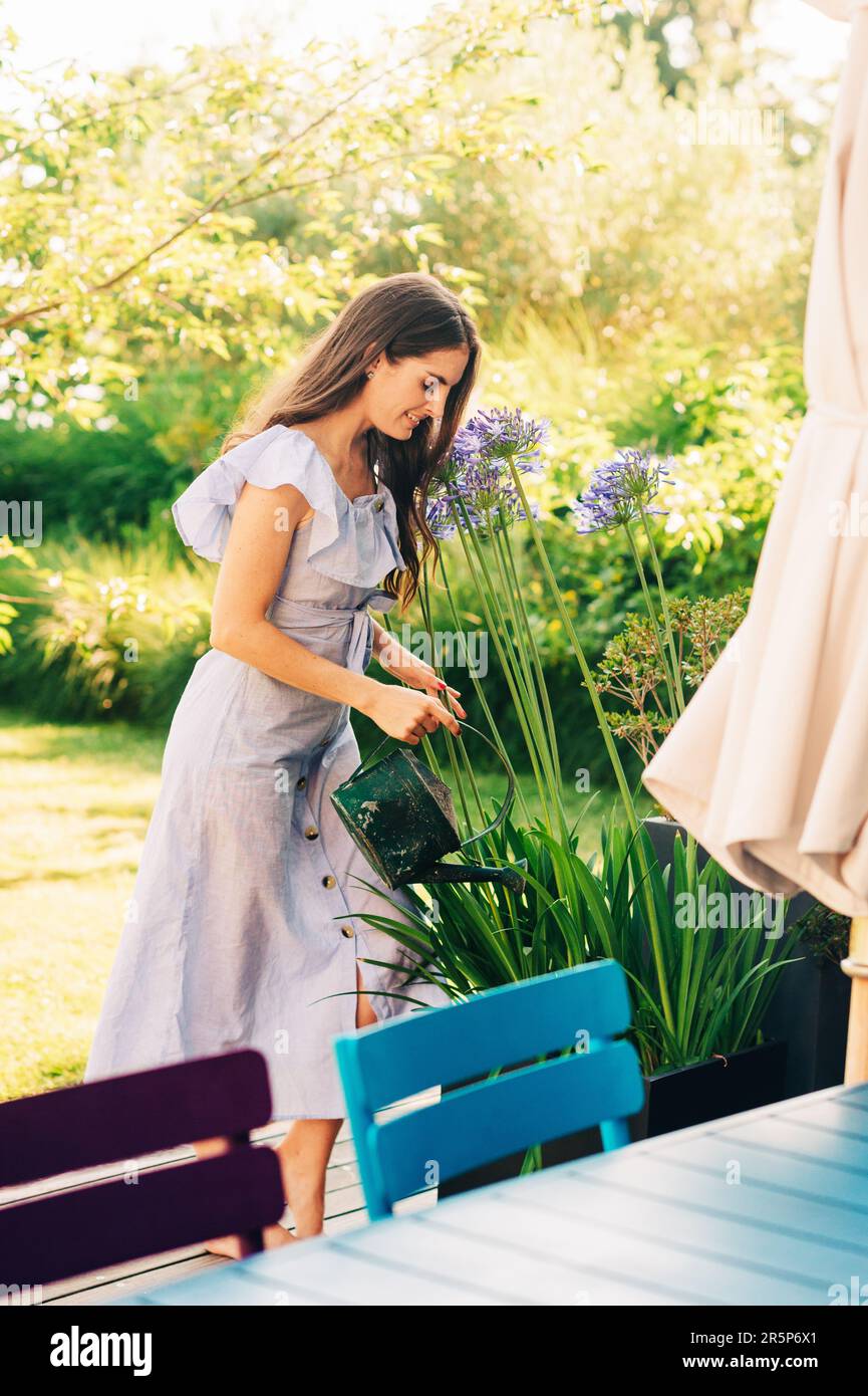 Jolie jeune femme arrosoir des plantes dans le jardin d'été Banque D'Images