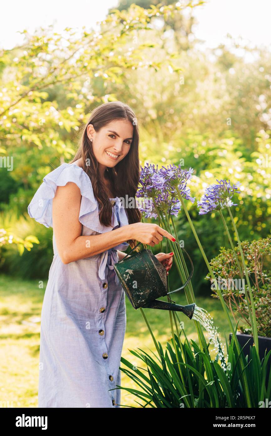 Jolie jeune femme arrosoir des plantes dans le jardin d'été Banque D'Images
