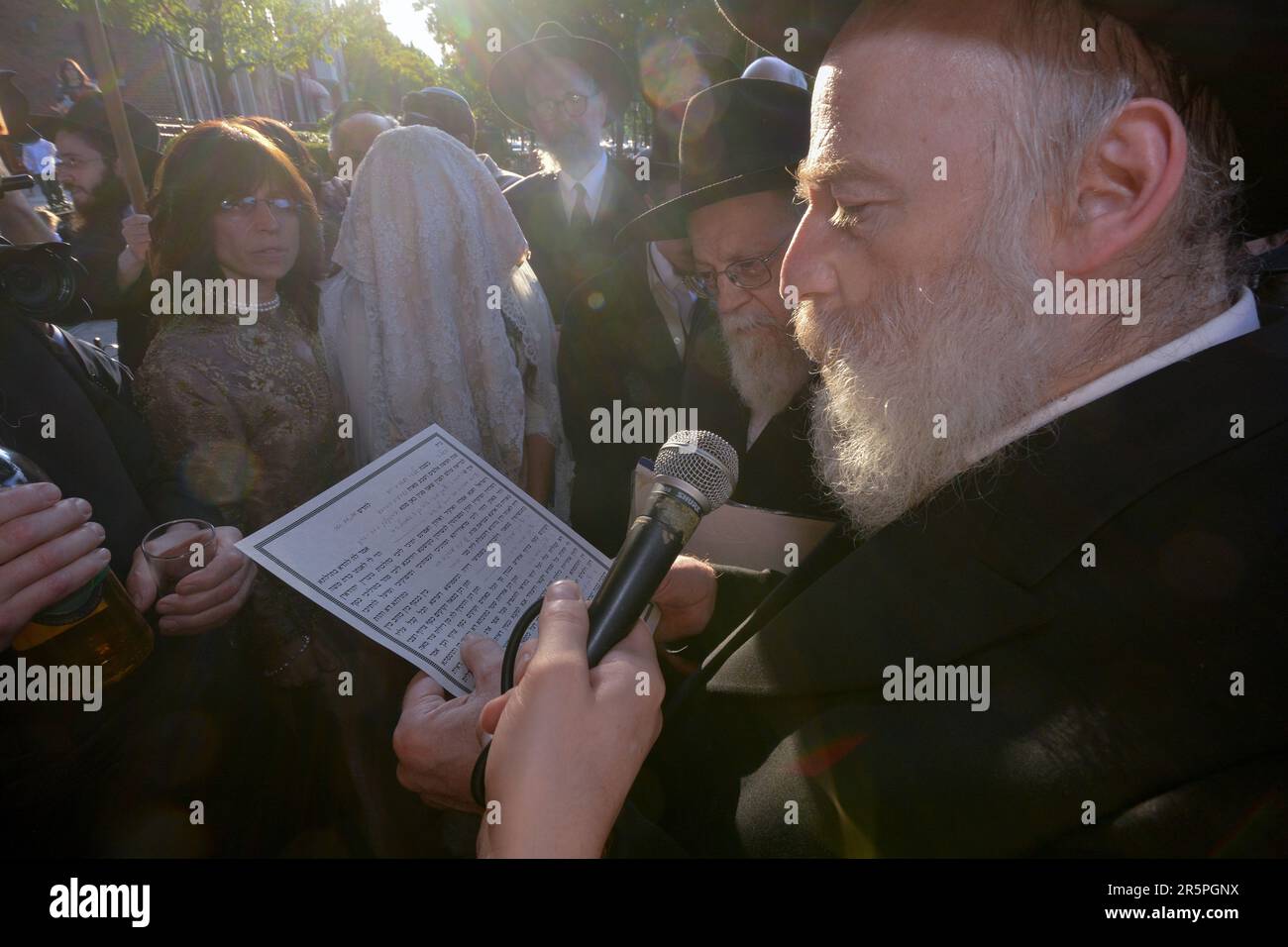 Lors d'une cérémonie juive orthodoxe de mariage, un parent lit à partir des bénédictions de 7. La mariée est en arrière-plan. À Brooklyn, New York. Banque D'Images