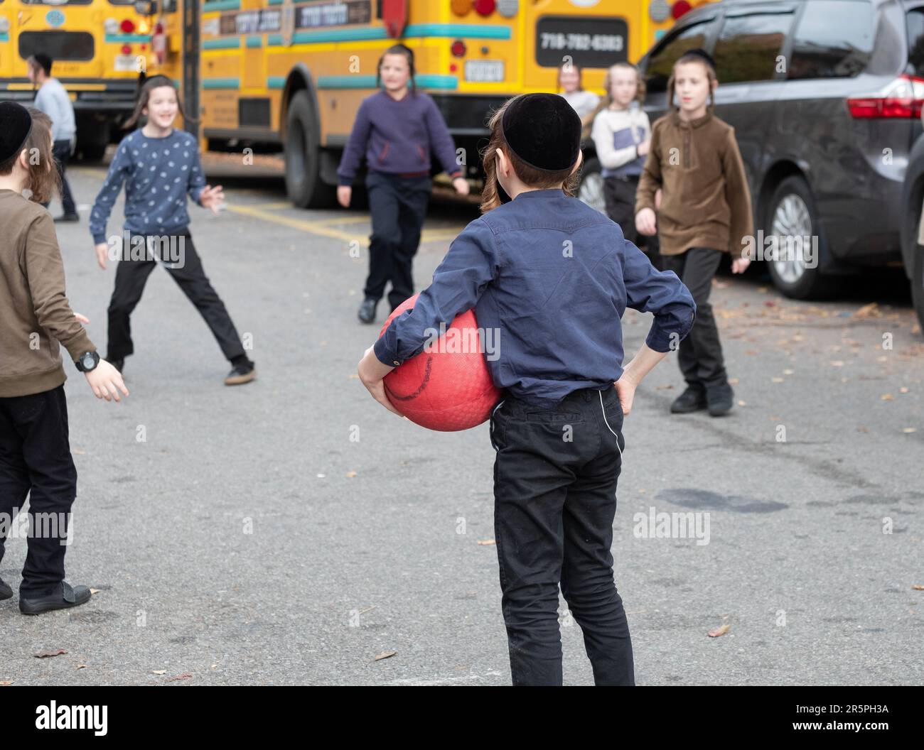 Pendant le congé de leur école de yeshiva, les étudiants juifs orthodoxes en skullcaps jouent dans une rue fermée. À Brooklyn, New York. Banque D'Images