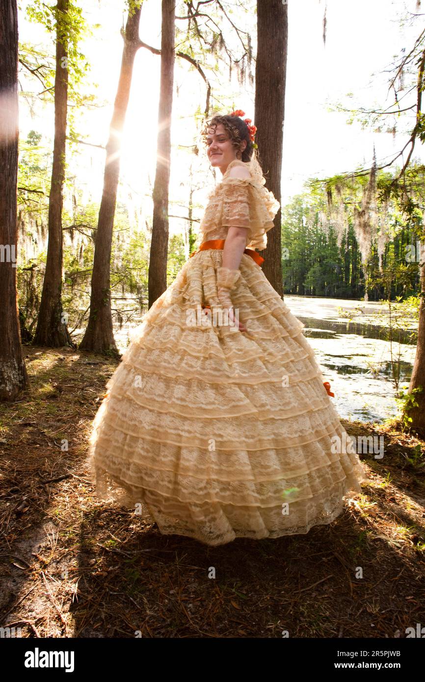 Une jeune femme pose dans une tenue Belle Sud , y compris une grande robe d'époque ornée, près d'un lac. Banque D'Images