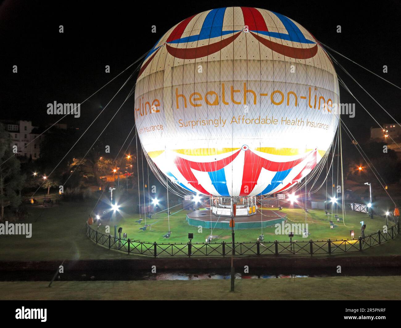 Ballon publicitaire captif illuminé pour Health-on-Line affiché la nuit dans le centre-ville de Yeovil, Somerset Banque D'Images