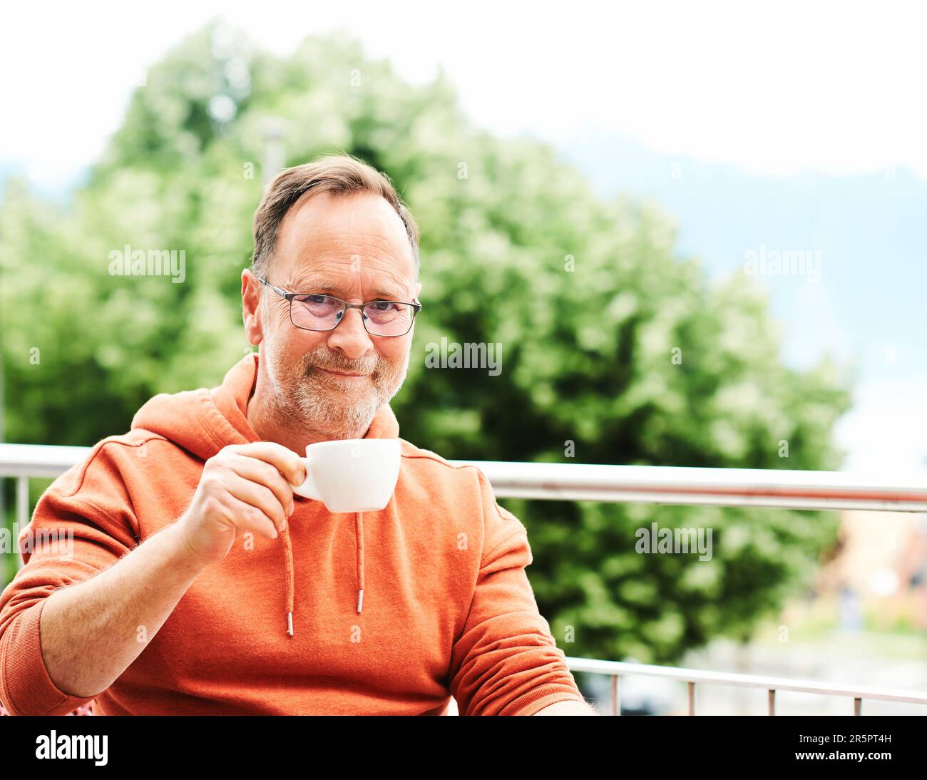 Homme d'âge moyen qui boit du café sur une terrasse Banque D'Images