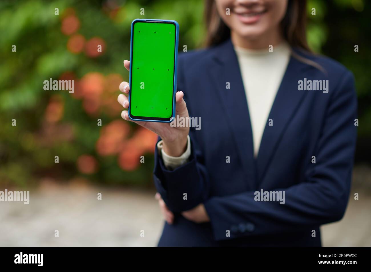 Image rognée d'une femme d'affaires montrant un smartphone avec un écran vert Banque D'Images
