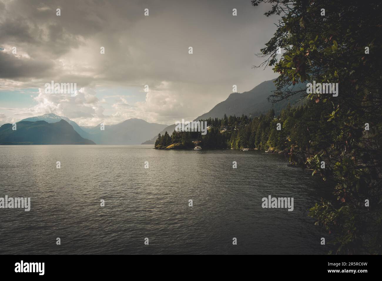 Des nuages sombres au-dessus d'une eau calme dans Howe Sound, vus de la région de la baie Lions, dans le nord de Vancouver, avec des montagnes rocheuses en arrière-plan Banque D'Images
