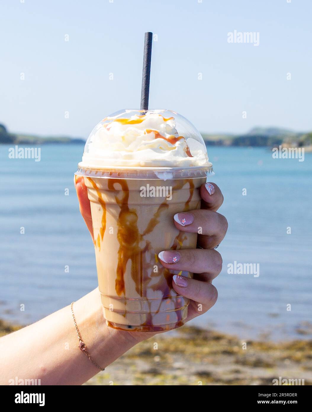 Main tenant le café glacé au caramel avec la boisson d'été à la crème fouettée. Banque D'Images