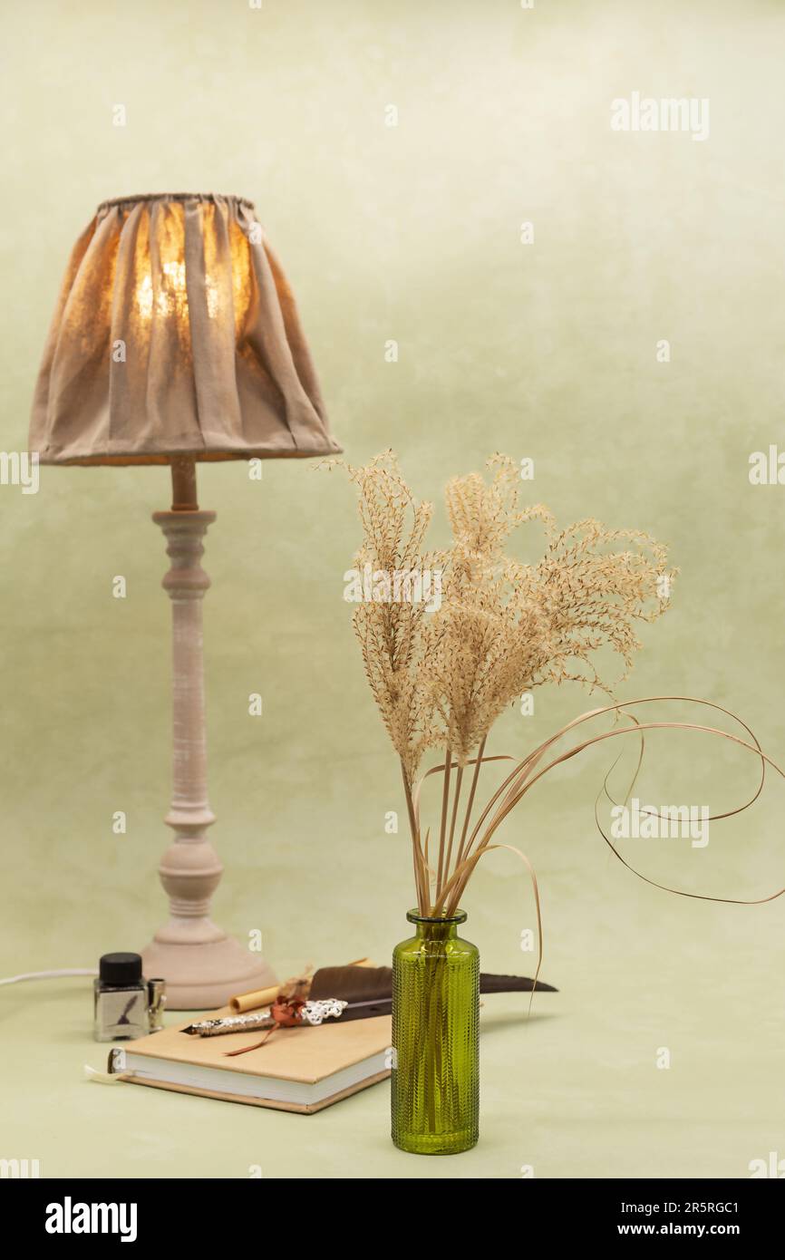 bouquet de fleurs séchées dans un vase avec une lampe sur fond olive de style boho Banque D'Images