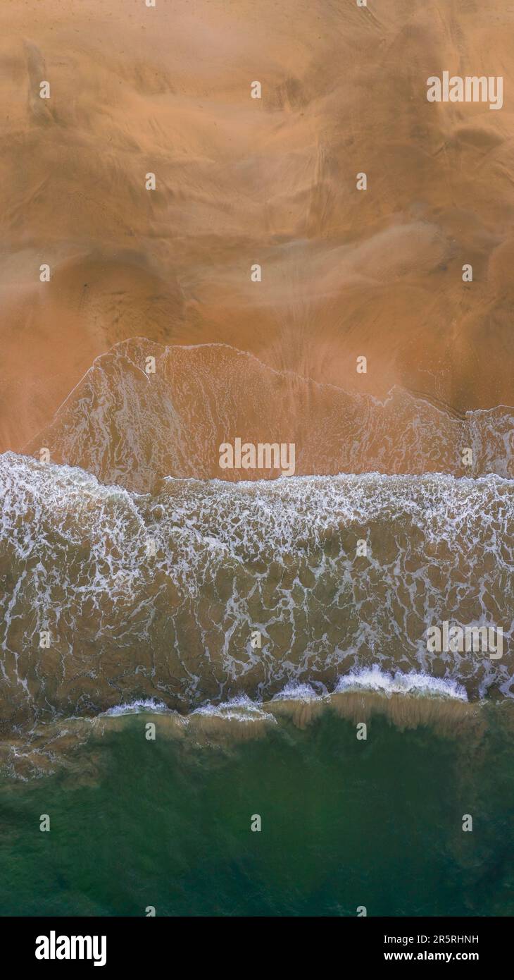 Une photo verticale de puissantes vagues de l'océan qui s'écrasant sur la plage de sable Banque D'Images