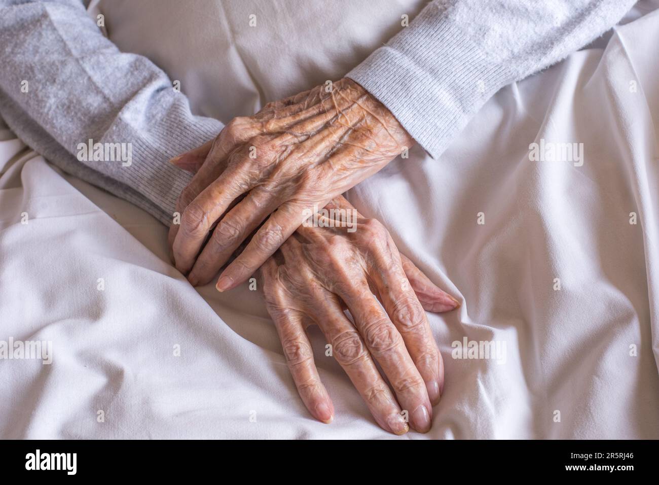Les mains d'une vieille femme près d'un lit dans un hôpital. Processus de vieillissement, femmes âgées. Banque D'Images