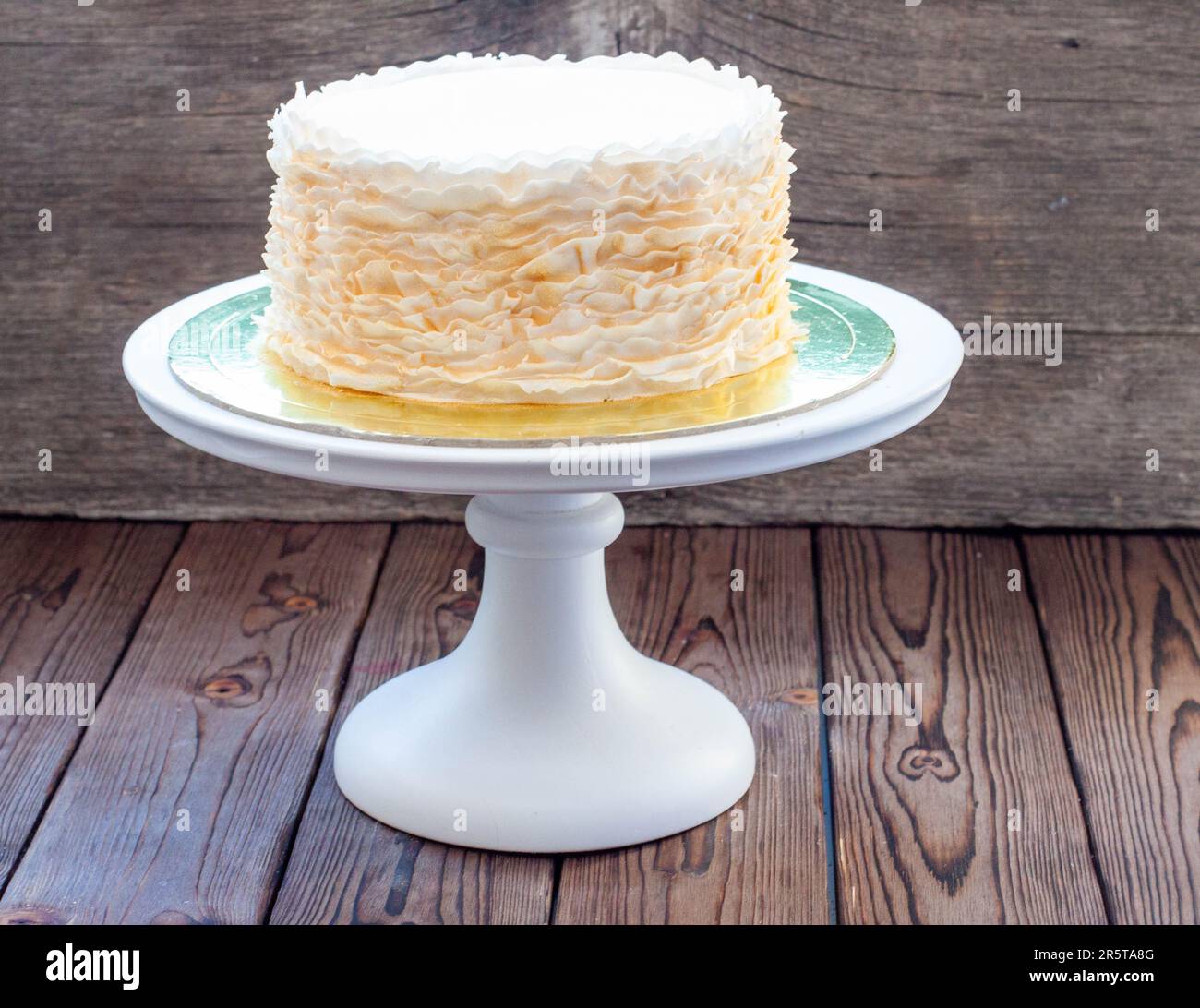 Gâteau à la volants doré et blanc sur fond rustique en bois Banque D'Images
