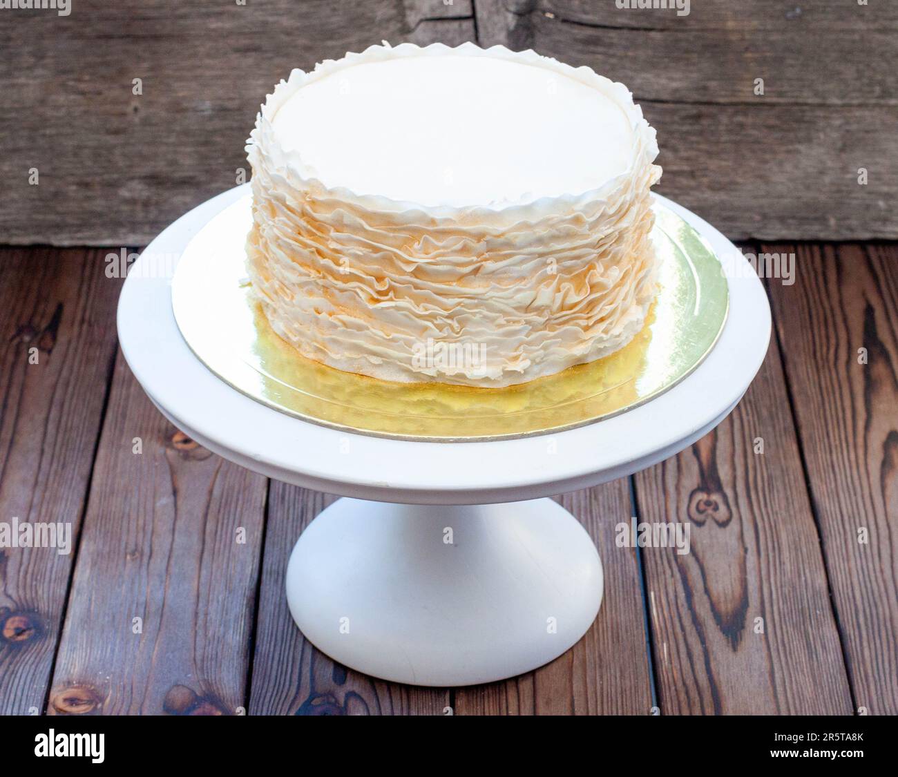Gâteau à la volants doré et blanc sur fond rustique en bois Banque D'Images