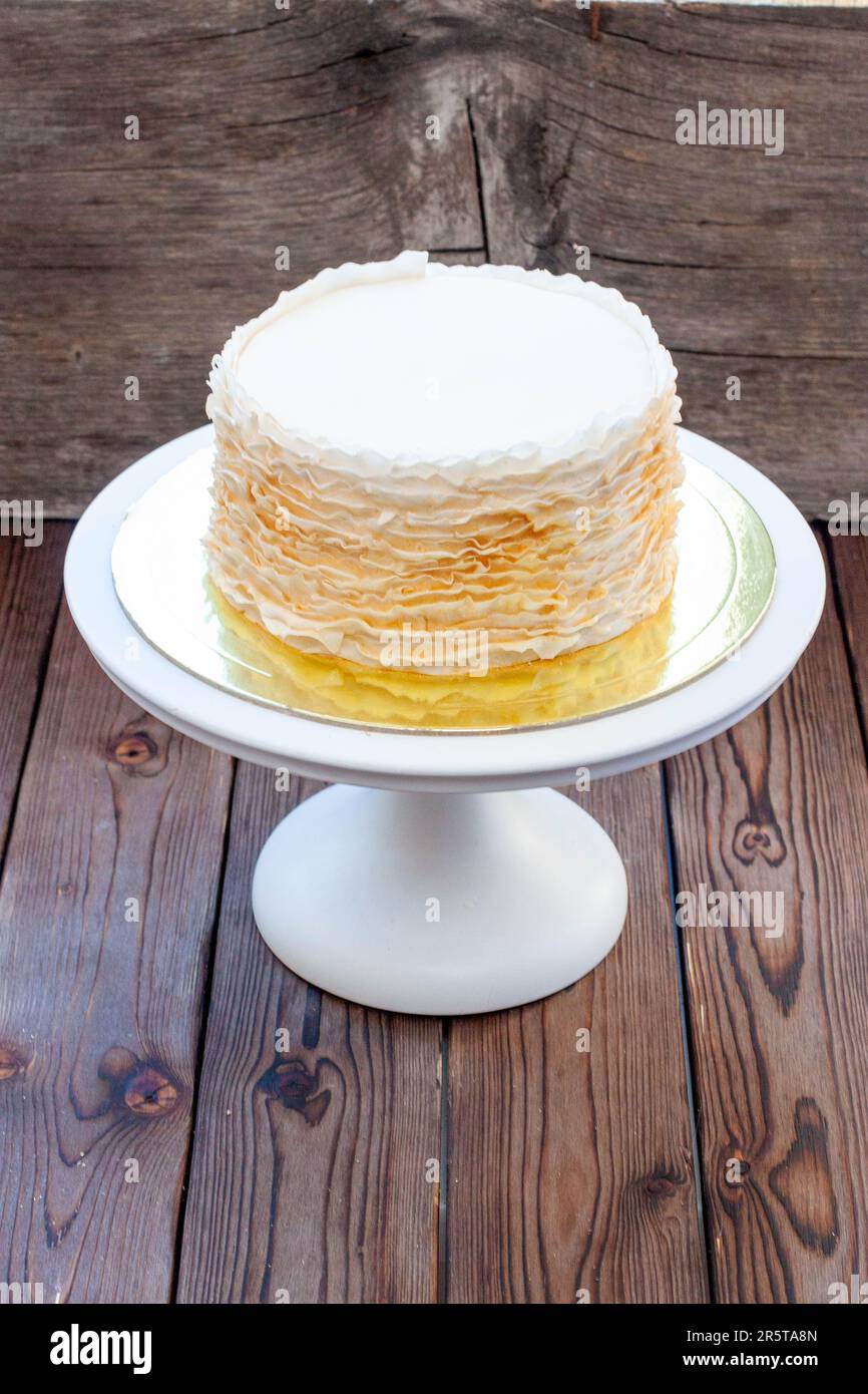 Gâteau à la volants doré et blanc sur fond rustique en bois Banque D'Images