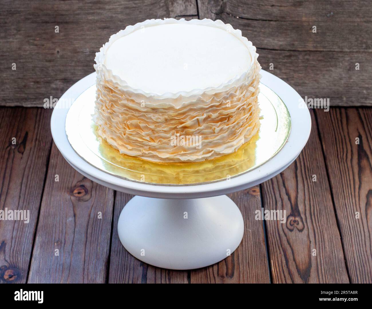 Gâteau à la volants doré et blanc sur fond rustique en bois Banque D'Images