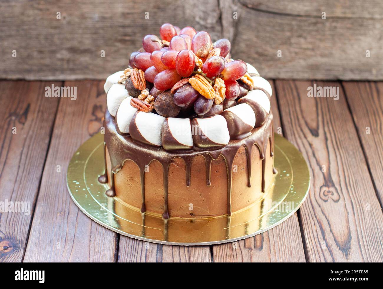 L'idée d'un gâteau d'automne fait de chocolat et décoré de raisins, de noix, de truffes au chocolat et de guimauves. Rustique backgrond, cuisine de confort Banque D'Images