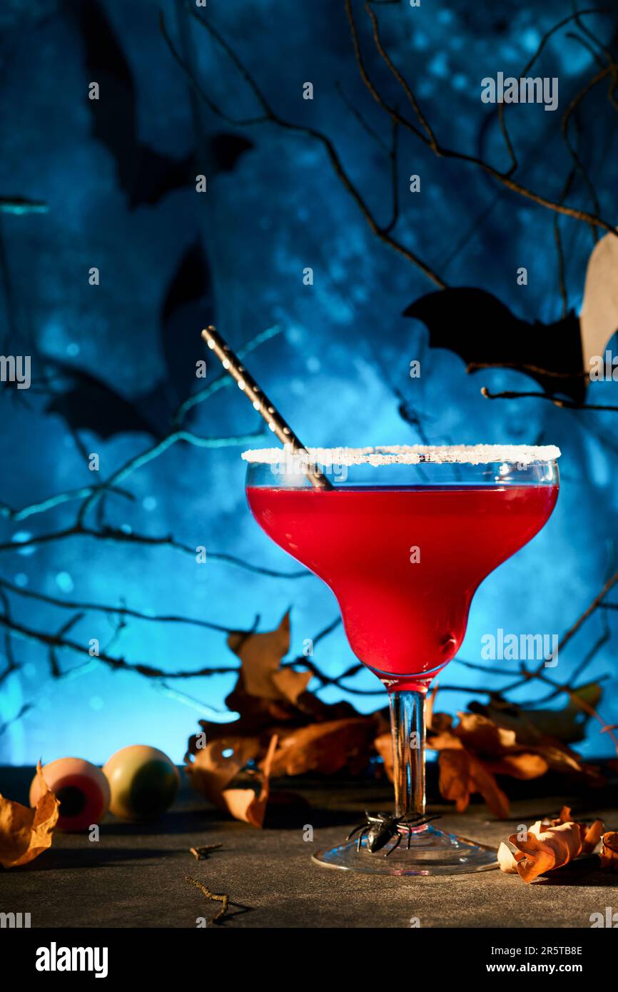 Halloween cocktail sanglant margarita. Cocktail rouge sanglant margarita et bouteille forment le crâne sur fond bleu sombre effrayant. Boisson de fête pour la fête avec Banque D'Images