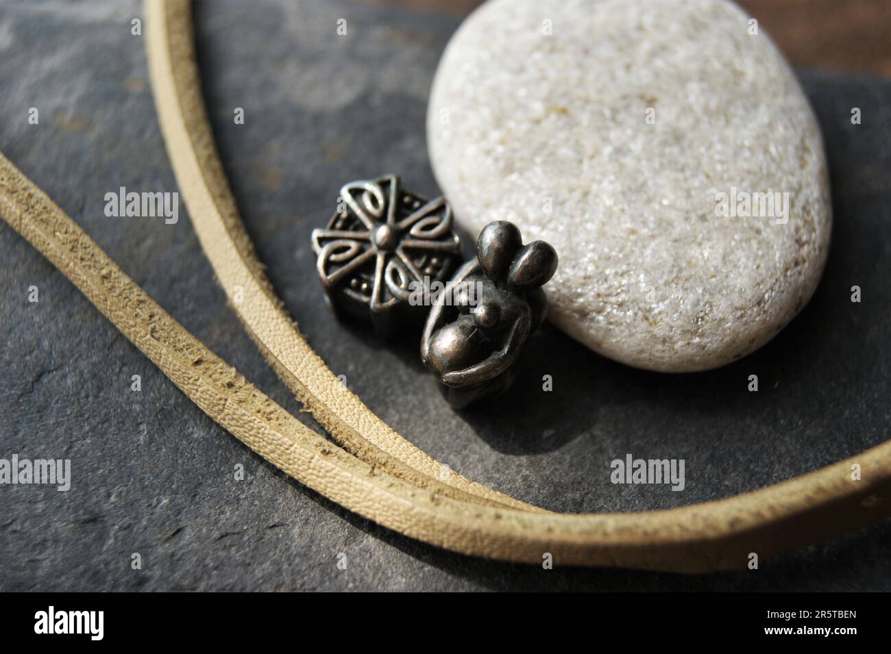 Bijoux en argent et bracelet en cuir. Pendentifs femme enceinte et croix. Banque D'Images