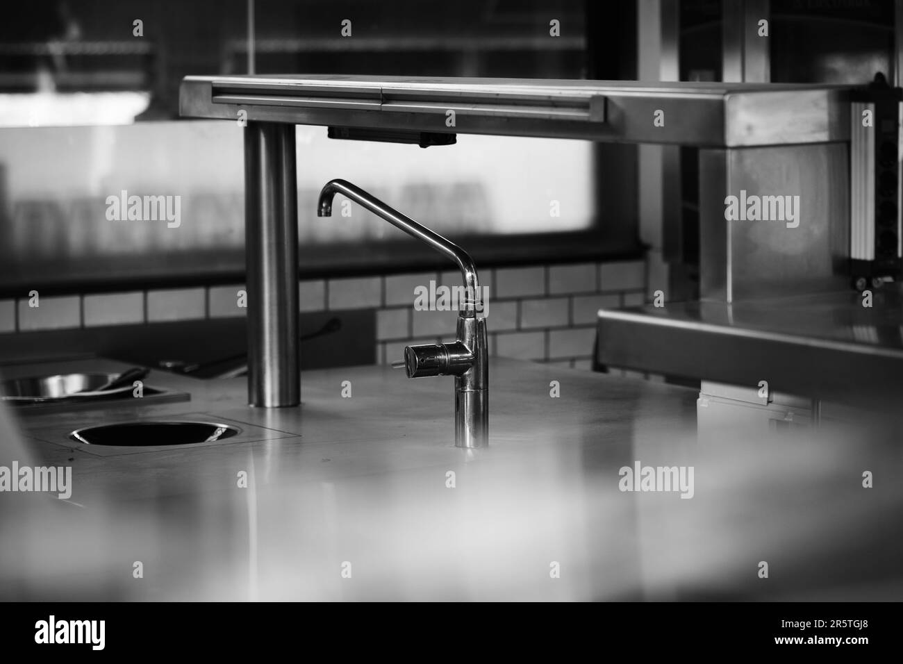 Un évier de cuisine de comptoir en acier inoxydable avec robinet de style industriel assorti dans une cuisine professionnelle Banque D'Images