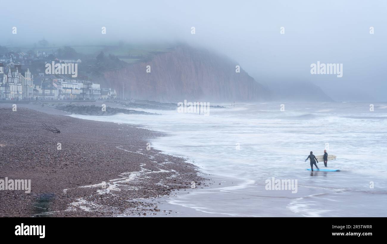 Deux hommes surfent sur la Manche au large de Sidmouth sur la côte jurassique de Devon. Banque D'Images