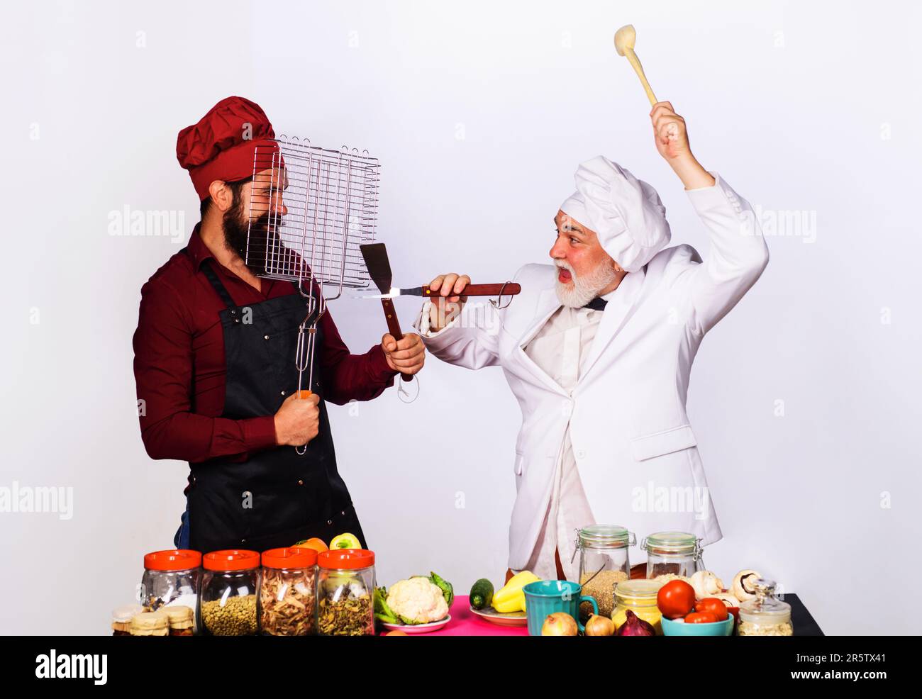 Cuisine professionnelle. Les chefs en uniforme participent au spectacle culinaire. Règles de la cuisine. Défi de cuisine. Bataille culinaire dans la cuisine. Deux cuisiniers ou boulanger Banque D'Images