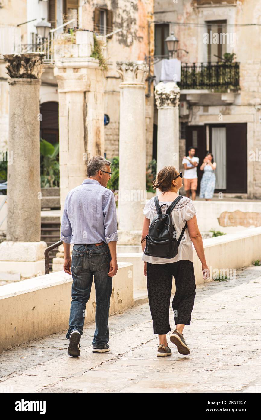 Couple de touristes marchant parmi les vestiges et les colonnes d'un temple romain dans la vieille ville de Bari, Puglia, Italie, verticale Banque D'Images