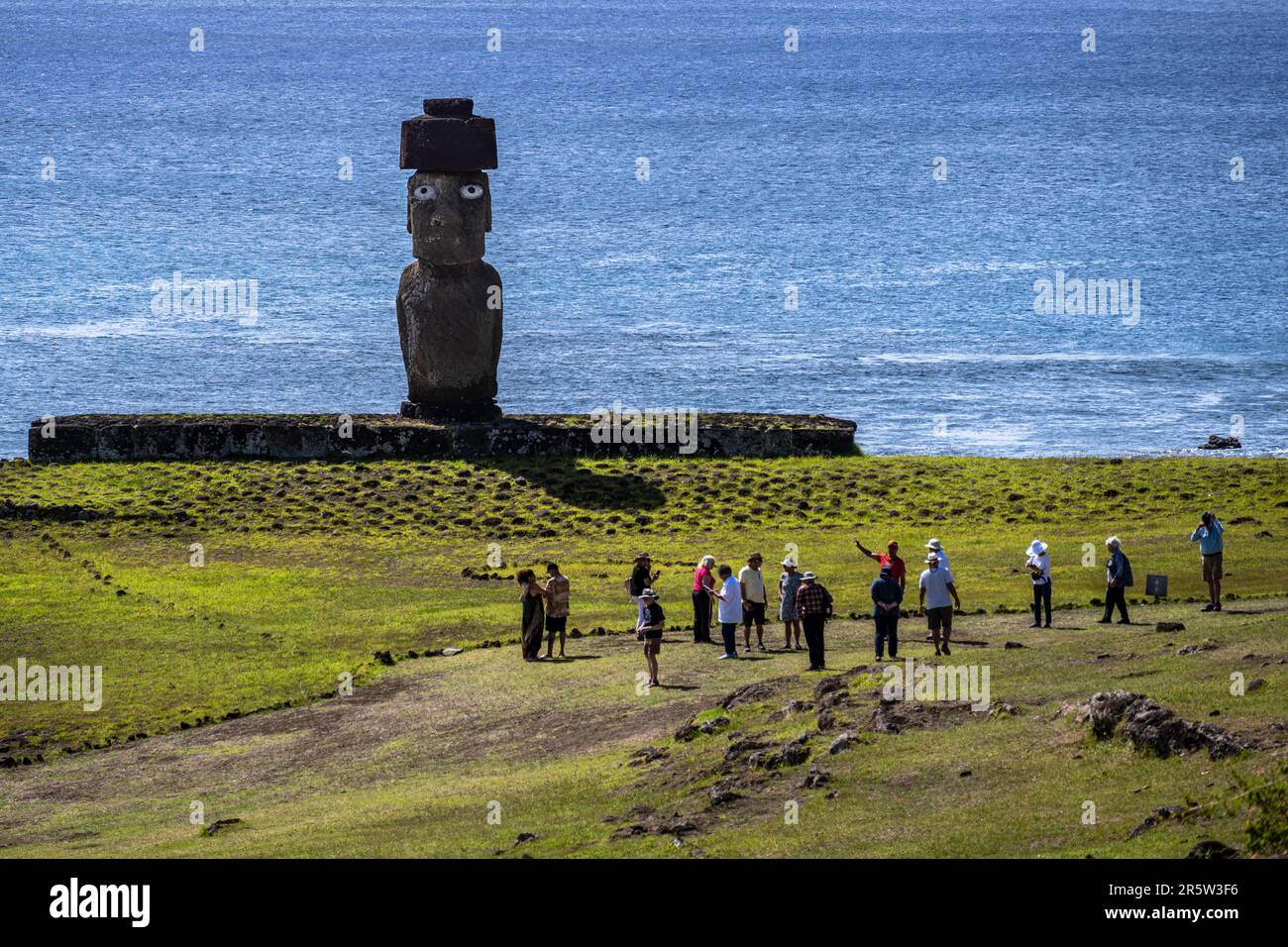 Île de Pâques, Chili -- 25 janvier 2023. Photo d'une statue de Moai orientée vers l'intérieur lorsqu'un groupe passe ; l'océan Pacifique est en arrière-plan. Banque D'Images