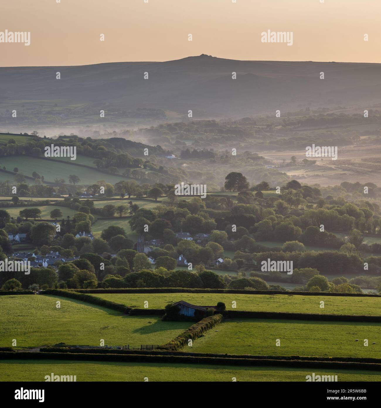 En regardant vers le nord-est depuis la colline de Brant Tor, le feu de l'aube tombe à la campagne autour de Brentor et Lydford dans le Devon occidental, avec Great Links Tor sur Dartmoor Banque D'Images