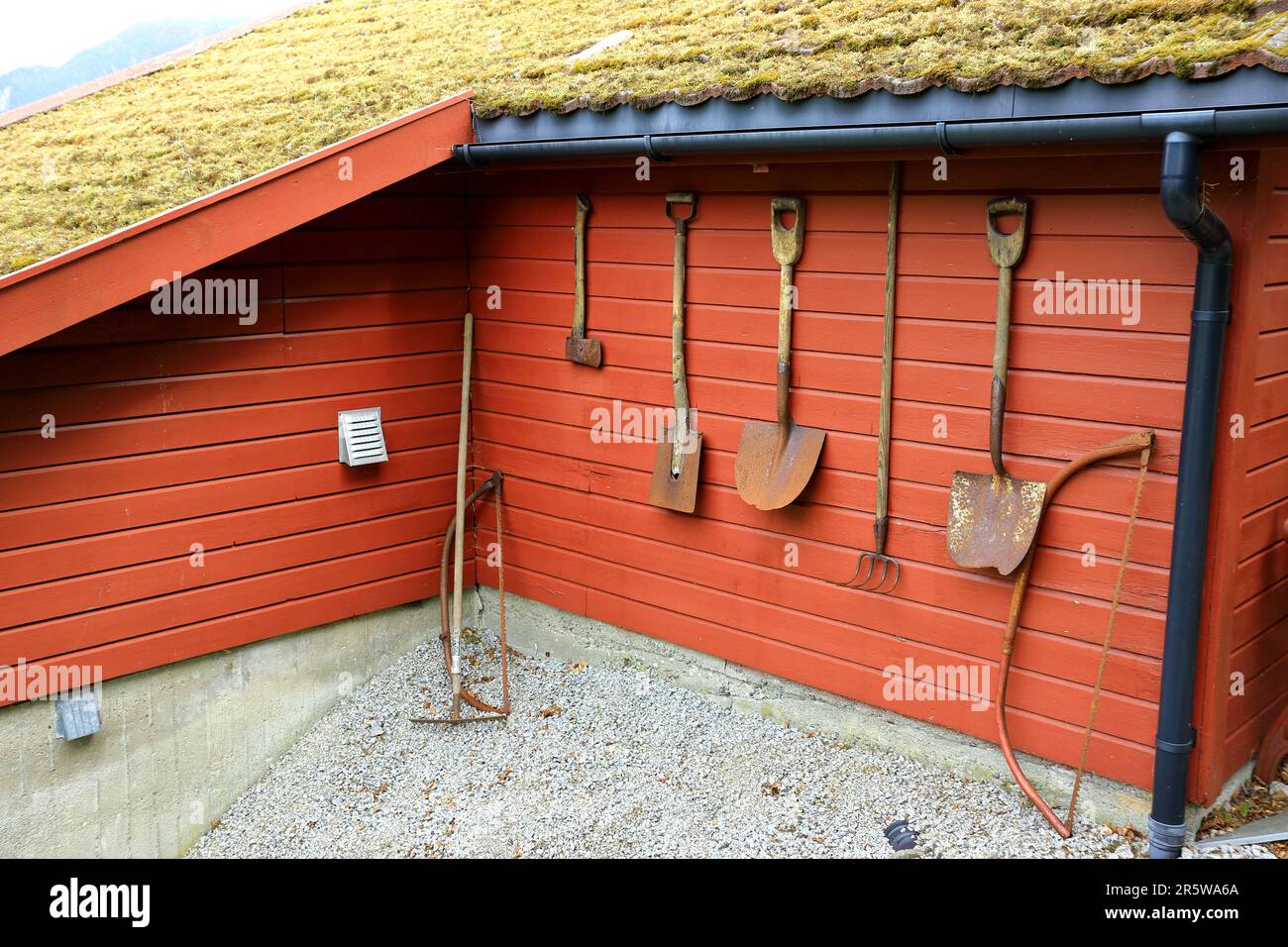Vieux outils de jardinage suspendus sur un mur de grange Banque D'Images