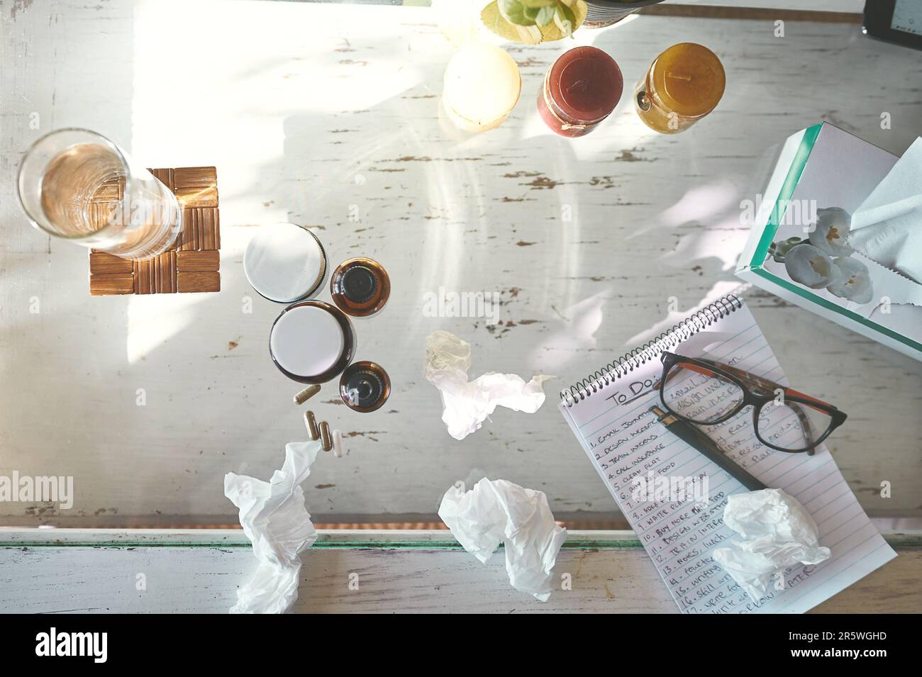 Le pack de démarrage Get Well Soon. Prise de vue en grand angle des médicaments, mouchoirs un bloc-notes et lunettes sur une table à la maison. Banque D'Images