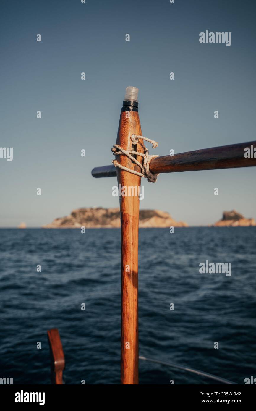 Une image rapprochée de l'arc d'un voilier, avec une corde drapée dessus, entouré d'un terrain rocheux Banque D'Images