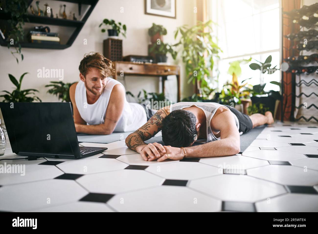 Il n'y a aucune honte dans un jeu de yoga faible. deux hommes prenant une pause après avoir passé par une routine de yoga en ligne à la maison. Banque D'Images