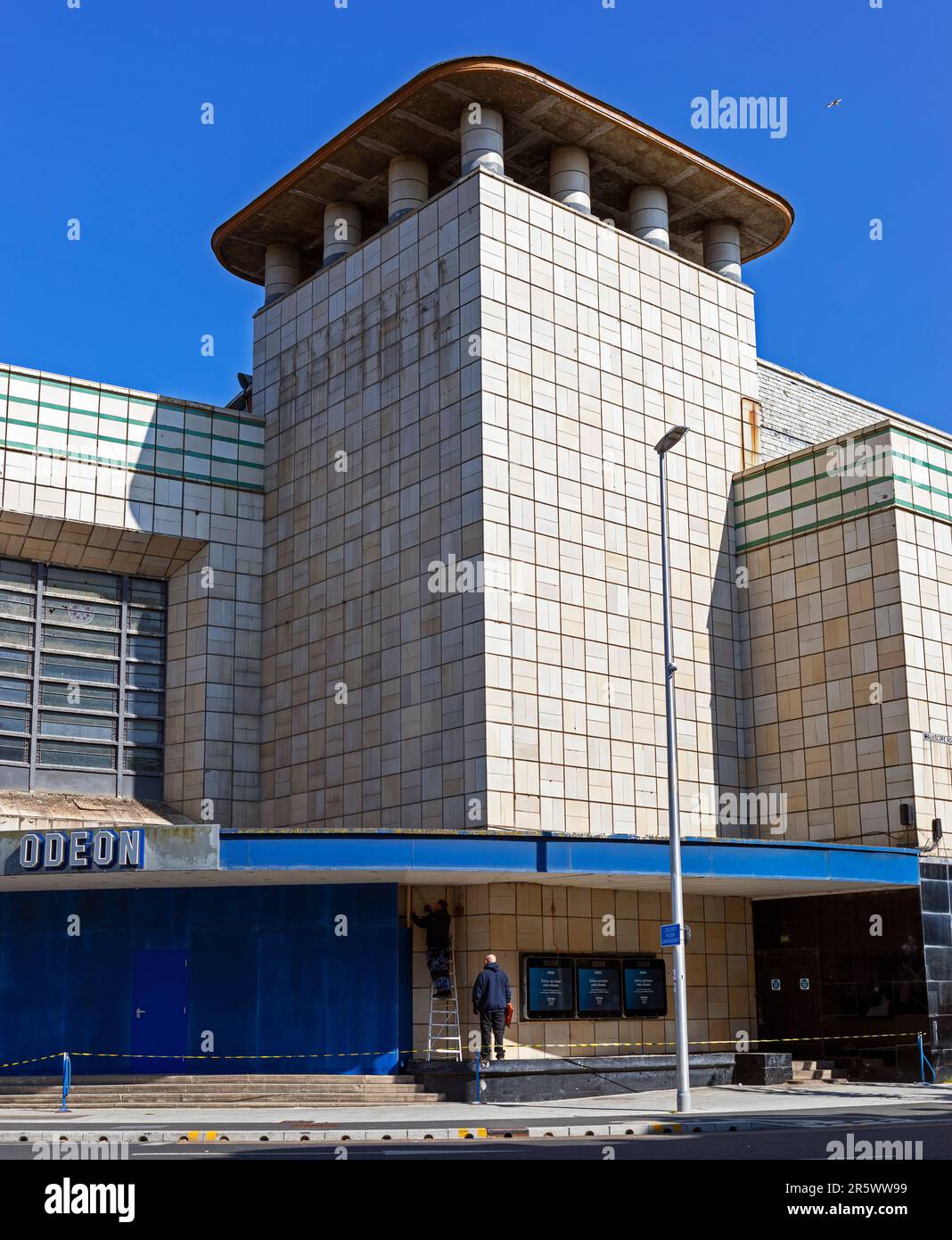 Weston-super-Mare, Royaume-Uni, 5 juin 2023. Le jour de la fermeture du cinéma Odéon, des ouvriers sont à bord de l'entrée principale. L'Odeon, qui a ouvert ses portes en 1935, est un bâtiment classé de catégorie II et est le seul de quatre bâtiments similaires conçus par Thomas Cecil Howitt pour survivre intacts. Son avenir est maintenant incertain. Banque D'Images