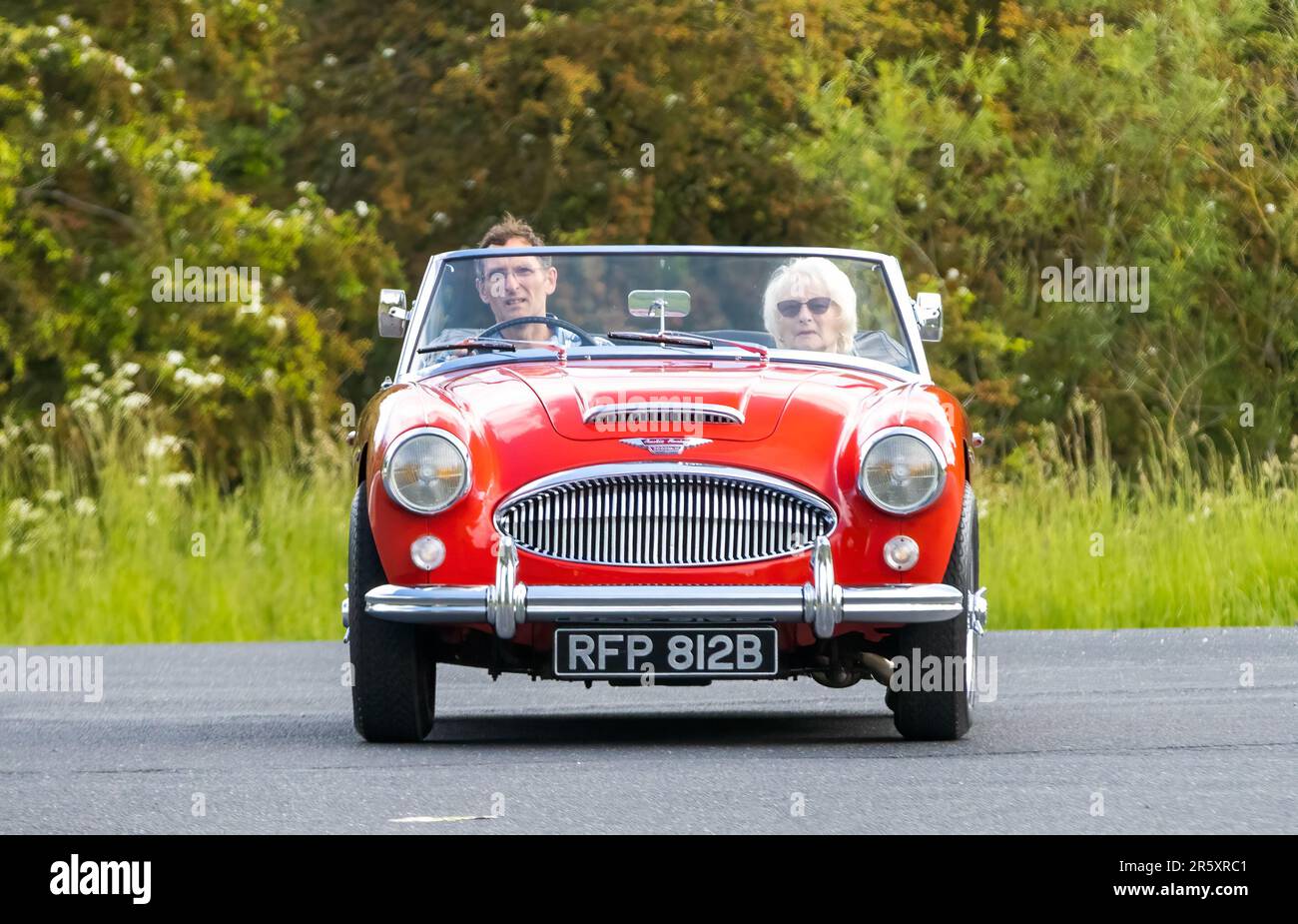 Stony Stratford, Royaume-Uni - 4 juin 2023: 1964 rouge AUSTIN HEALEY 3000 voiture classique voyageant sur une route de campagne anglaise. Banque D'Images